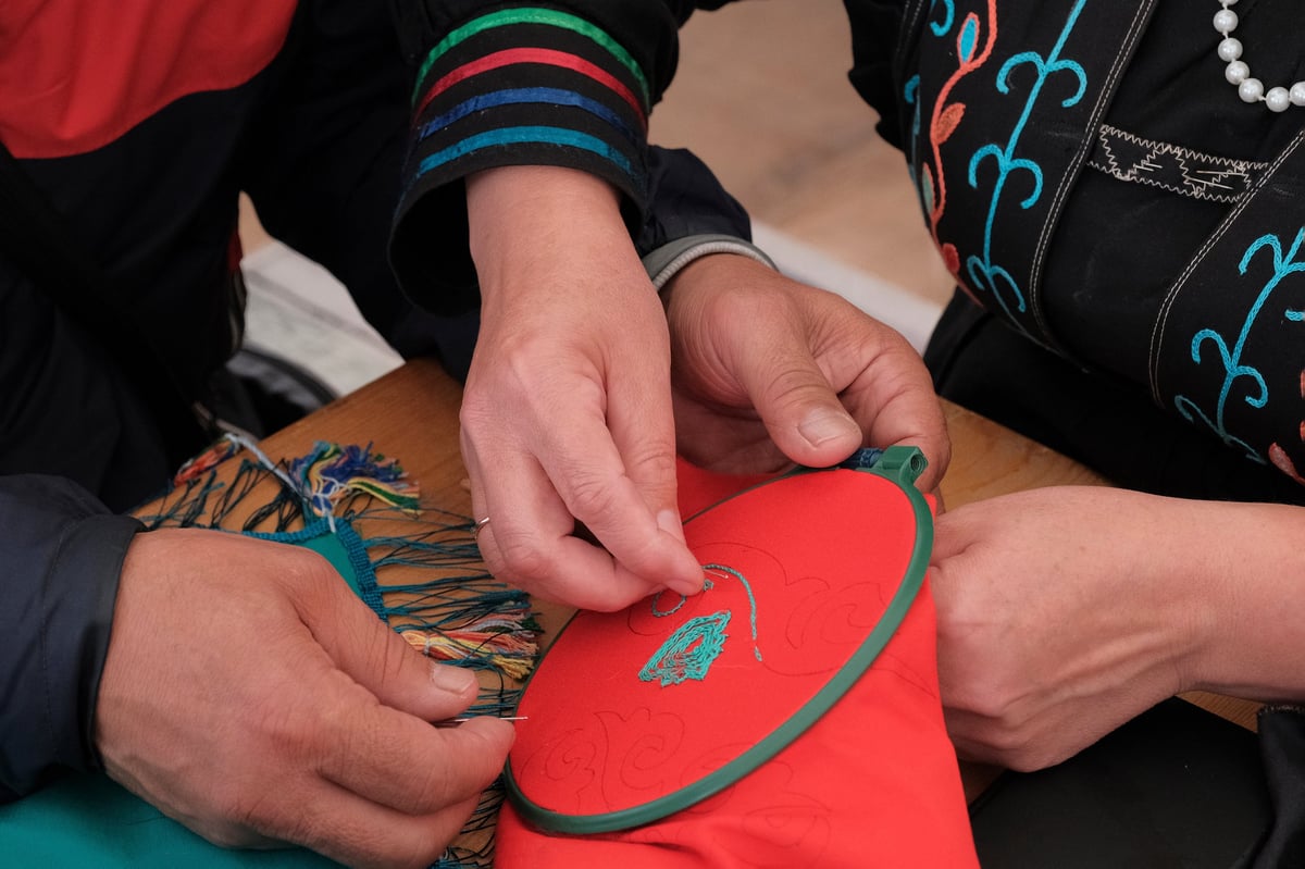 Hands embroidering a traditional pattern by warm light in a heritage workshop